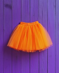 Poster - Halloween costume minimal flat lay of orange tulle skirt on purple wood surface