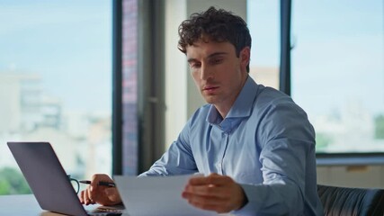 Wall Mural - Hardworking man reading documents working on laptop in home office closeup.