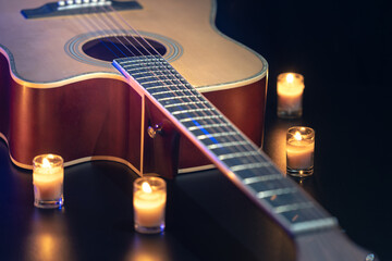 Acoustic guitar on a black background with candles.