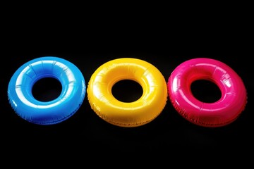 Poster - Three colorful inflatable pool rings floating on a dark background, perfect for water-themed designs or illustrations