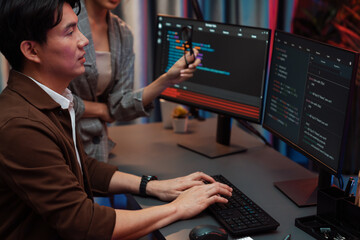 IT developers discussing with point to intelligent website development coder system running data online two screens information technology at neon light room at modern office. Infobahn.