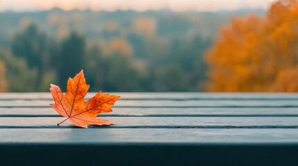 Poster - Single orange maple leaf resting on a wooden table