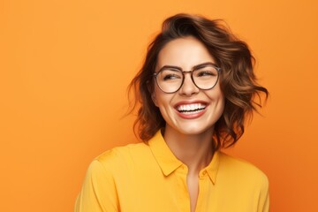 Poster - Portrait of happy smiling young woman in glasses, over yellow background