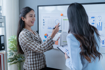 Two businesswomen are having a productive meeting in the office, analyzing financial data and developing strategies for success