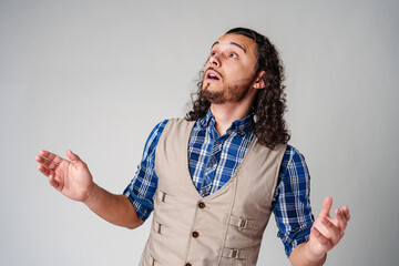 Young man with curly hair expresses surprise in a light-colored setting