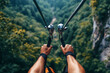 © tynza - A close-up shot of hands gripping the zip-line handlebars as the rider speeds over a forest valley.