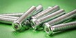 © Collection - A close-up of shiny screws with a square drive head, laying in a haphazard pile against a vibrant green background.