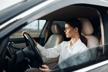 Woman driving car, hands on steering wheel, looks at camera, driver's seat, daytime