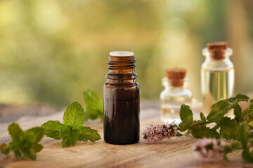 Wall Mural - A brown bottle of aromatherapy essential oil with fresh peppermint leaves and flowers