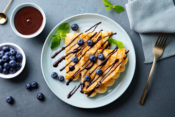 Wall Mural - Crepes, thin pancakes with chocolate sauce and fresh blueberries. Grey background. Top view.