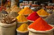 © Krisz G - A vibrant outdoor market with large mounds of spices, from bright saffron to deep brown cinnamon sticks, arranged in sacks and bowls, capturing the sensory overload of a spice bazaar