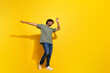 © deagreez - Full size photo of good mood guy dressed khaki t-shirt jeans scream raising hands up dancing in club isolated on yellow color background