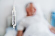 © InsideCreativeHouse - Close up shot of medicine in and iv drip and patient on background in hospital room