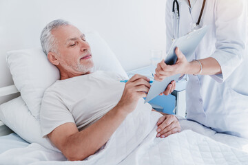 Close up of doctor giving papers for signature to senior patient. Healthcare and medicine concept.