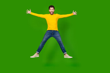 Canvas Print - Full body photo of attractive young man jump spread hands legs dressed stylish yellow clothes isolated on green color background