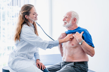 Smiling woman doctor is using stethoscope to diagnose elderly patient