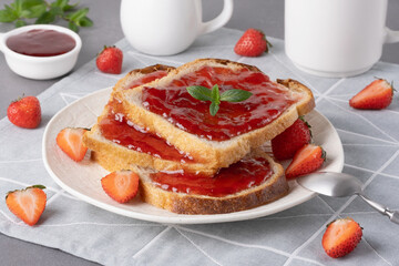 Bread with tasty strawberry jam on grey table