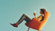 © Erika - una mujer sentada en una silla o sofa tomando un taza de cafe caliente relajada y tranquila disfrutando de un momento de descanso sobre una pared azul con espacio de copia