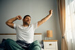 © Drazen - Man stretching in his bed after waking up in morning.