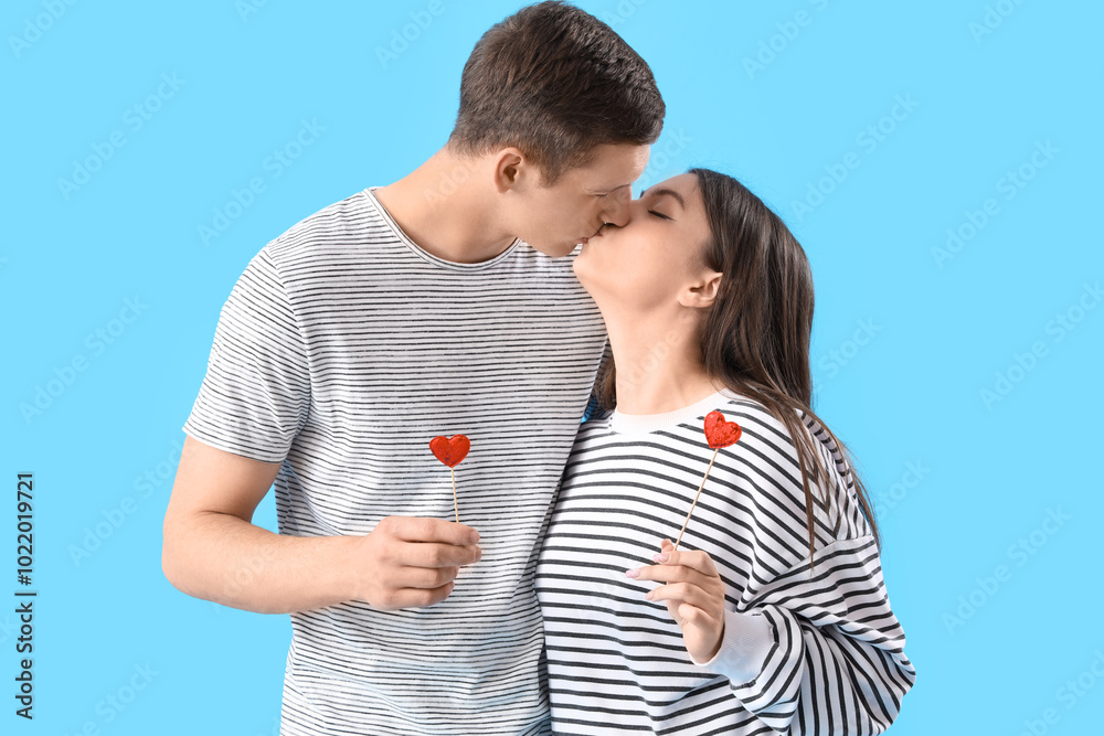 Happy young couple with hearts kissing on blue background