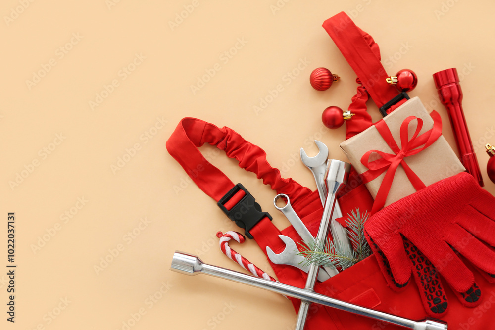Worker's supplies with Christmas decor and gift on beige background