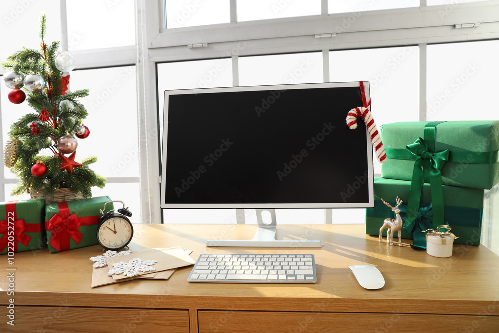 Workplace with computer monitor, presents and Christmas tree in office
