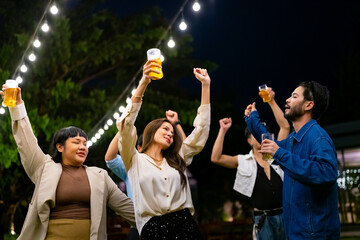 Group of Happy Asian millennial generation people friends enjoy and fun celebration reunion meeting outdoor dinner party with drinking beer and dancing in the garden at restaurant on holiday vacation.