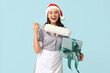 © Pixel-Shot - Beautiful female chambermaid in Santa hat with pp-duster and gift box on blue background