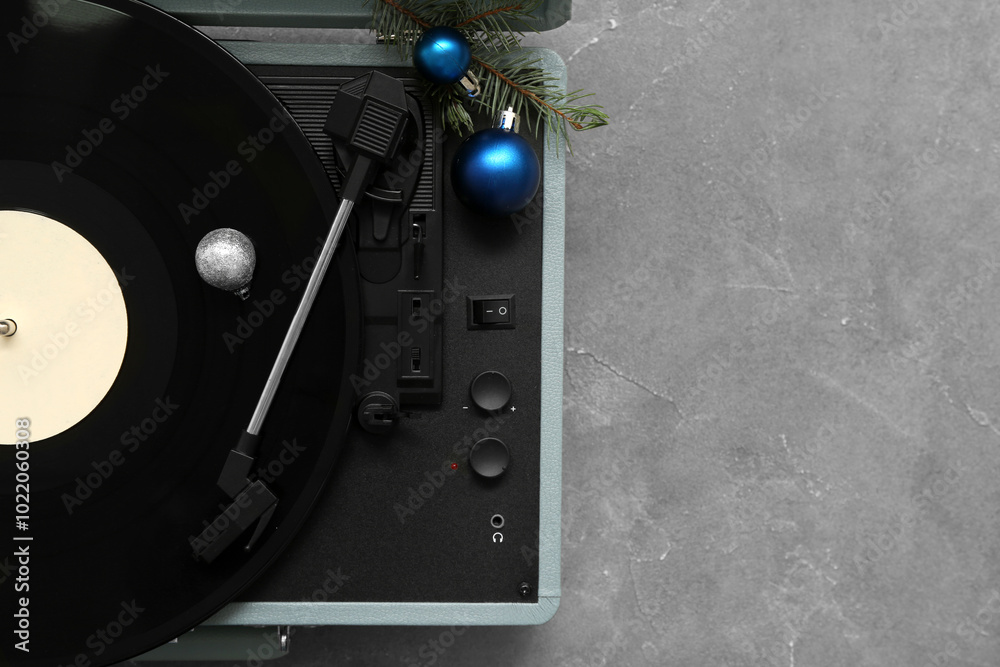 Vintage turntable with vinyl record and Christmas decorations on grey grunge background