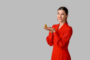 Wall Mural - Beautiful young happy woman with golden dragon figurine on grey background. Chinese New Year celebration