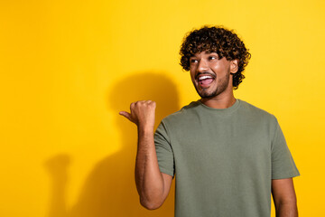 Wall Mural - Photo of ecstatic guy with curly hairstyle dressed khaki shirt look directing at sale empty space isolated on yellow color background