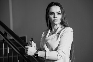 Graceful Elegance: A Woman in Monochrome Stands Thoughtfully at a Staircase