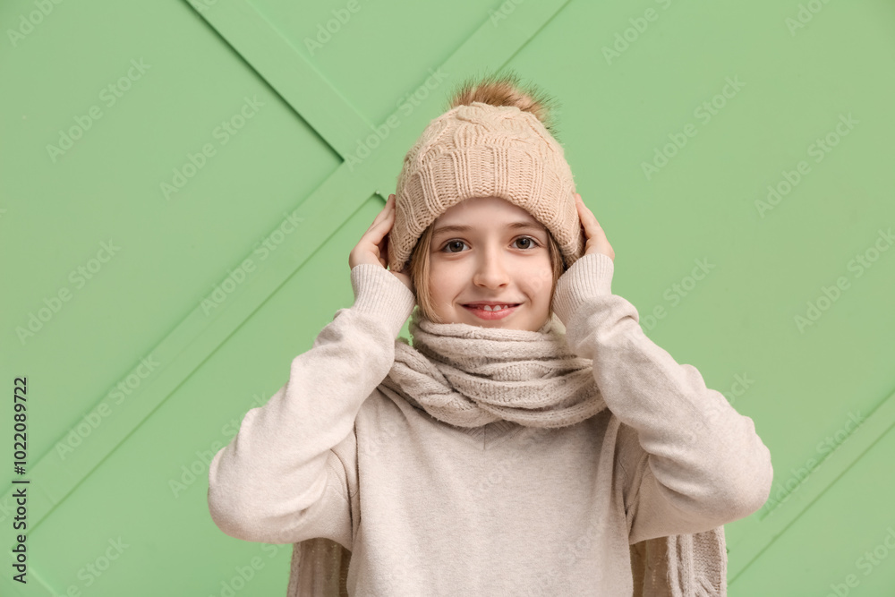 Cute little happy boy in winter clothes on green background