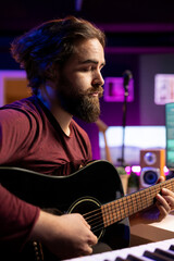 Leinwandbilder - Musician creating a song by playing acoustic guitar in home studio, recording tunes and singing on microphone. Audio engineer mixing and mastering his music with stereo gear, soundtracks.