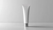 © Izzain - A white tube of lotion with a silver cap sits on a white surface. The tube is empty and ready for your product label.