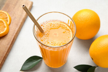 Glass of tasty juice and fresh oranges on white background