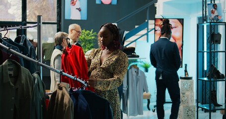 Canvas Print - African american pregnant client checks t shirts on hangers, looking to buy more comfortable pregnancy clothing items. Woman customer examining colorful clothes on display. Camera B.