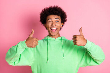 Canvas Print - Photo of nice young man eye wink thumb up wear green hoodie isolared on pink color background