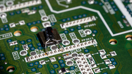 Poster - A green circuit board with a black component on it