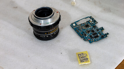 Aufkleber - A camera lens and a circuit board are laying on a white surface