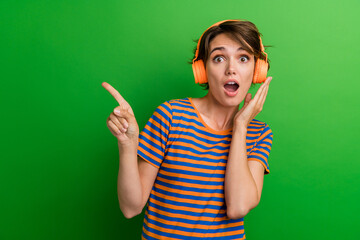 Sticker - Photo portrait of pretty young girl pointing empty space astonished reaction wear trendy striped outfit isolated on green color background