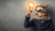 © Eddy Drmwn - A young girl wearing goggles points to a lightbulb above her head, symbolizing a new idea or inspiration.