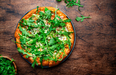 Wall Mural - Small pizza with blue cheese, ham, pesto and fresh arugula, wooden background, top view