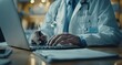 © btiger - Doctor using laptop and digital tablet for medical records in hospital office with stethoscope, online meeting, health care professional