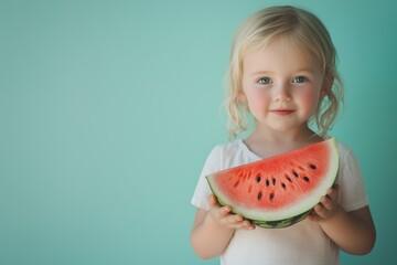 Young child holding a large slice of watermelon against a pastel blue background