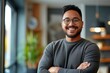 © Ameer - Successful male entrepreneur smiling confidently with arms crossed in modern office setting