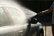 © Antonioguillem - Woman hand using hosepipe to wash a car in backlight