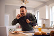 © Drazen - Man in  rush eating sandwich in kitchen.