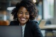 © Ameer - Happy and smiling African-American businesswoman working on laptop at modern office desk in professional workspace
