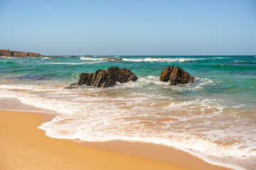 Portugal, beach Almograve. Coastline of Atlantic Ocean with sand and black rocks 